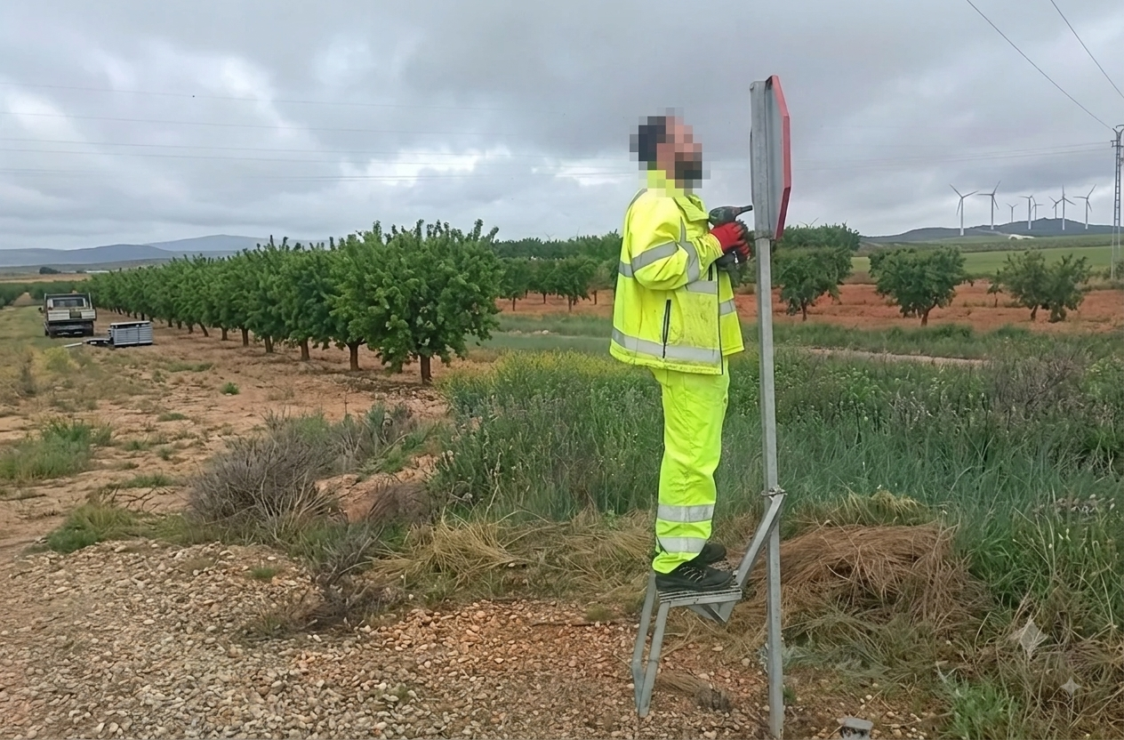 Operario trabajando en poste de señalización con dispositivo portátil