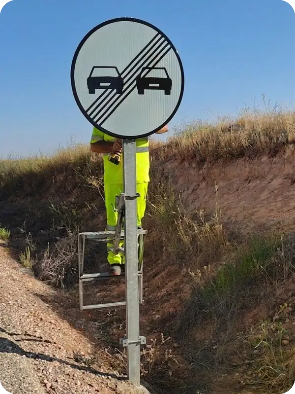 Operario trabajando en poste de señalización con dispositivo portátil